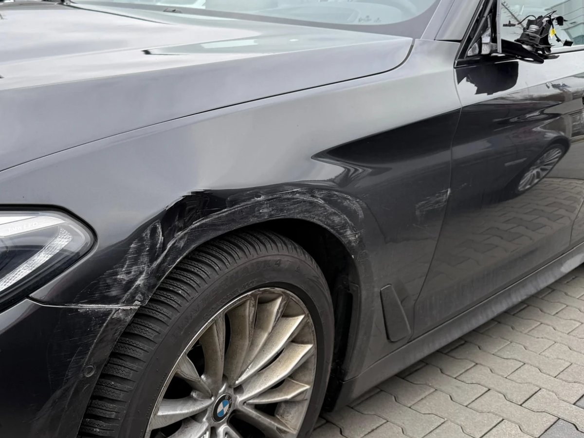 Grey BMW with scratch damage on the front wing and a torn-off wing mirror
