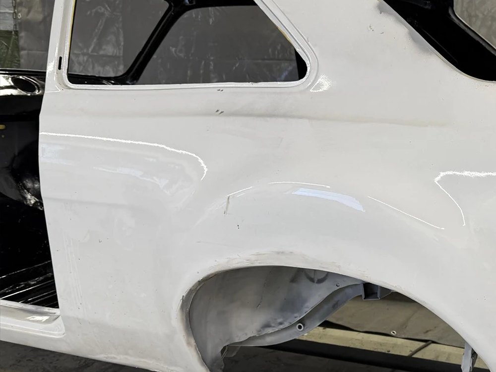 Weiß lackiertes Seitenteil einer Oldtimer-Karosserie in der Restaurierung